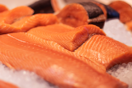 Fresh raw salmon steaks with pepper corns, salt, lemon and olive oil on black background. Healthy...