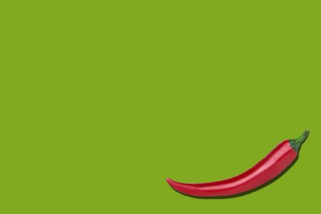 Single red chili pepper on a green background with copyspaceの写真素材