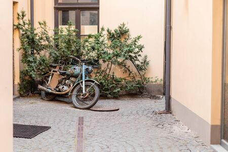 Retro motorbike on a street in old town on background green tree during covid 19 corona virus pandemic shut down.の写真素材