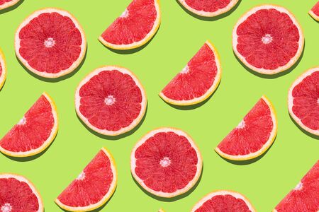 Flat lay fruit pattern of fresh grapefruit slices on green background. Minimal summer fruits pattern...