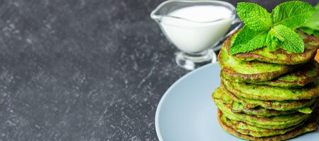 Nutrition and diet food, delicious green spinach crepes on blue plate with yogurt sauce on dark background with copyspaceの写真素材