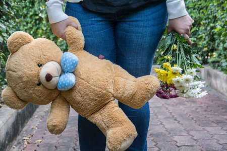 Woman holding a doll and flowersの写真素材