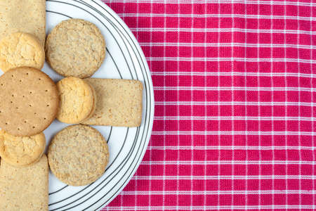 Assorted biscuits arranged on a white pattened plate on a red and white rustic napkin