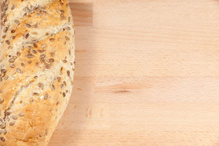 Loaf of bread coated with honey and topped with sunflower seeds and pieces of fruit laying on a...