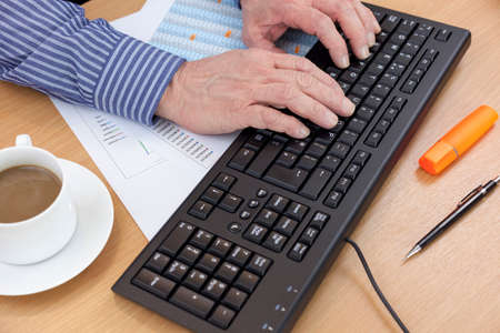 Accountant at his desk using a computer keyboard to check a financial report
