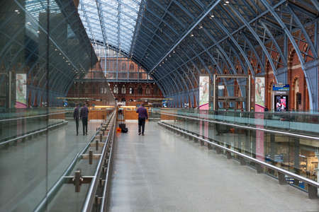 LONDON, UK - JULY 26, 2016: Man using cell phone walking along the upper walkway under the Barlow Shed roof at St Pancras railway stationのeditorial素材