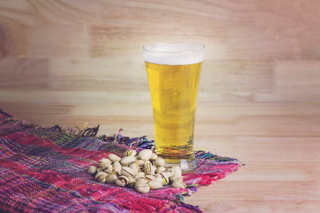 Glass beer and pistachios on wood backgroundの写真素材