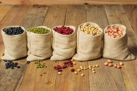 Different kinds of beans in sacks bag on wooden backgroundの写真素材