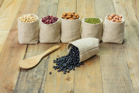 Different kinds of beans in sacks bag, focus on scattered black beansの写真素材