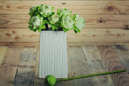 folded lotus flowers in vase on wooden backgroundの写真素材