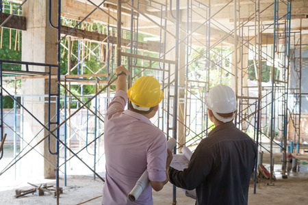 Engineer and Architect working at Construction Site with blueprint
