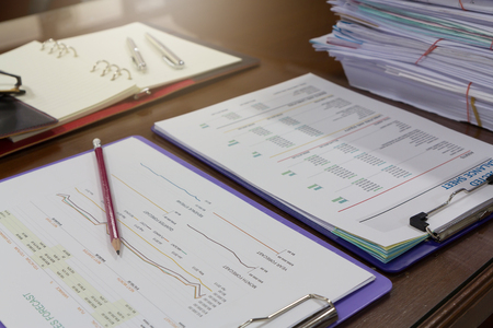Business and finance concept of analysis chart on office desk with stack of business paper backgroundの写真素材