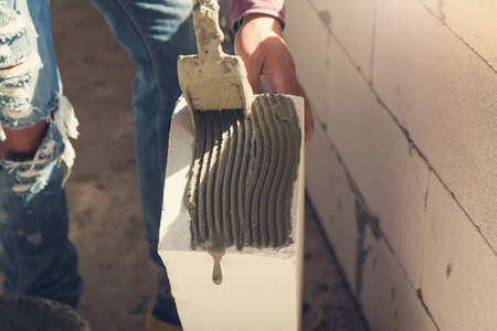 Construction concept, Bricklayer worker installing wite blocks to build wall at construction siteの写真素材