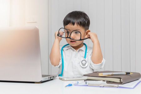 Young asian boy playing doctor and using computer laptop.の写真素材