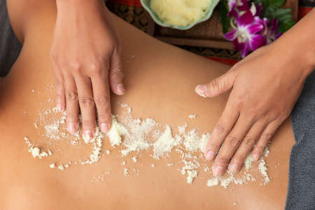 Asian woman enjoying a salt scrub massage at spa.の写真素材