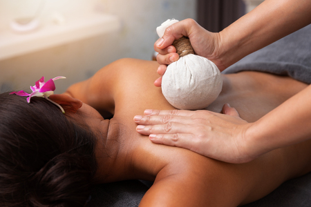 Asian woman enjoying compress balls, herbal ball massage at spa.の写真素材