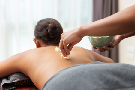 Asian woman enjoying a salt scrub massage at spa.の写真素材