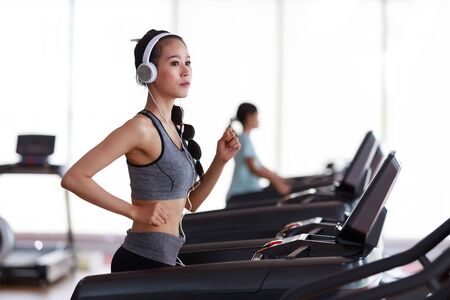 Fitness woman wearing headphone cardio workout at fitness gym.