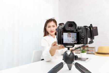 Young travel blogger girl reviewing in front of camera and recording video at home for vlog.の写真素材