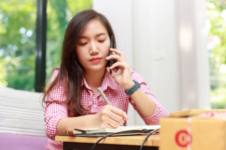 Seller using smartphone to get order and prepare to send goods to customer after checking order.の写真素材