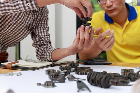 Engineer discussing and designing about mechanical gear parts in office.