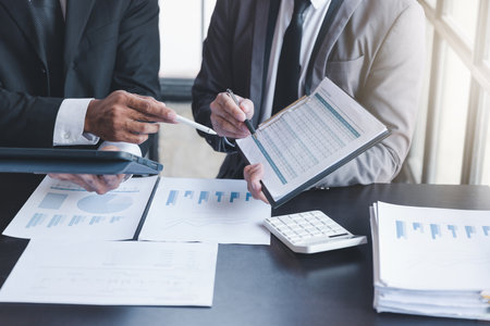 Finance and investment concept, Businessman present business finance investment plan with his partner, Investor colleagues discussing new investment plan by financial graph data on office table with laptop and digital tablet.の写真素材