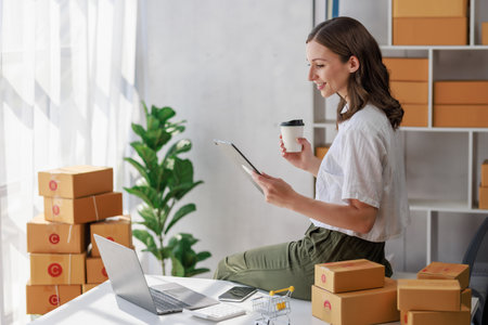 Concept of parcel delivery and selling online,Retailer Using a calculator to calculate sales for the day on an online store for pack into the parcel box and prepare to send the product to the customerの写真素材