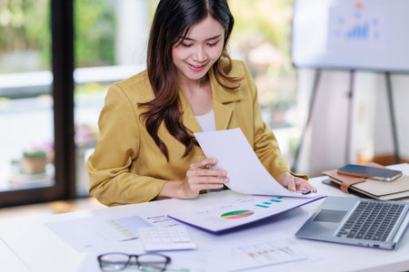 Concept of business office woman working,Businesswoman working about her invesment plan with analyzing document and business investment graph data by using laptop on desk in workstation.の写真素材