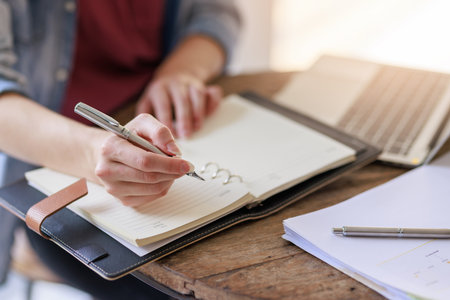 Education concepts, Close up high school young female student or college student sitting and writing on notebook for homework research while wating for class in universityの写真素材