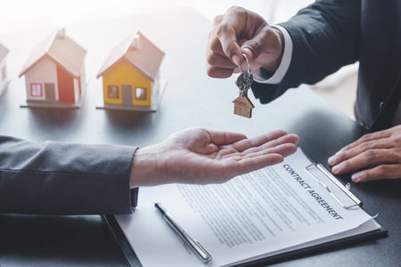 Home sales,home rental and real estate concept.Hands of estate agent giving keys to the Customer after sign the document while explain about the terms of the home purchase or rental agreementの写真素材