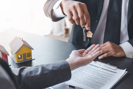 Home sales,home rental and real estate concept.Hands of estate agent giving keys to the Customer after sign the document while explain about the terms of the home purchase or rental agreementの写真素材