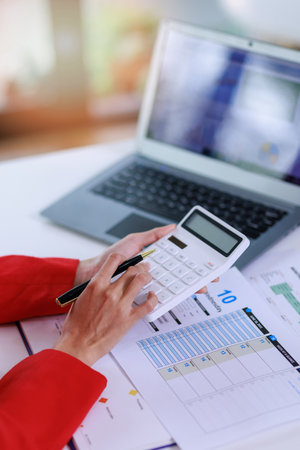 Concept of business invesment or woman working,Closeup businesswoman checking her invesment plan with analyzing document and business investment graph data by using calculator and computer laptopの写真素材