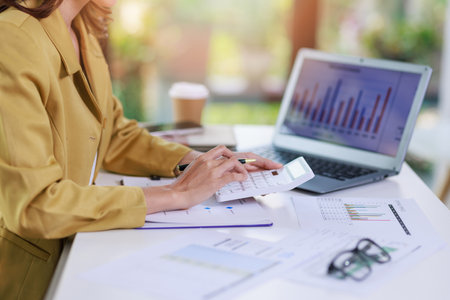 Concept of business invesment or woman working,Closeup businesswoman checking her invesment plan with analyzing document and business investment graph data by using calculator and computer laptopの写真素材