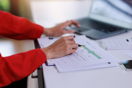 Concept of business invesment or woman working,Closeup businesswoman checking her invesment plan with analyzing document and business investment graph data by using calculator and computer laptopの写真素材