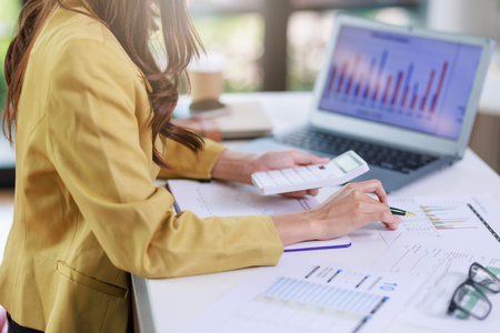 Concept of business office woman working,Closeup businesswoman checking her invesment plan with analyzing document and business investment graph data by using calculator and laptopの写真素材