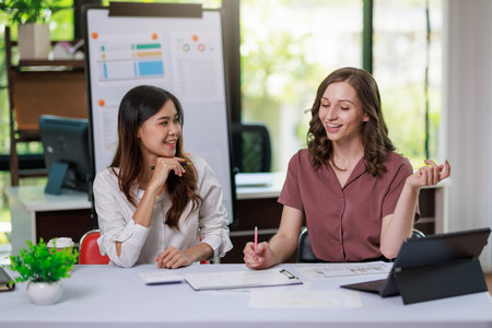 Concept of business office woman working,Businesswoman smile while working about her invesment plan with analyzing document and business investment graph data by using laptop on desk in workstation.の写真素材