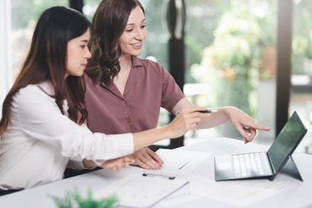Concept of business office woman working,Businesswoman smile while working about her invesment plan with analyzing document and business investment graph data by using laptop on desk in workstation.の写真素材
