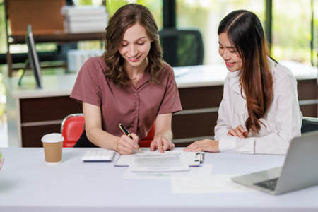 Concept of business office woman working,Businesswoman smile while working about her invesment plan with analyzing document and business investment graph data by using laptop on desk in workstation.の写真素材