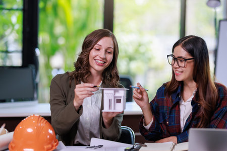 Construction concept of Engineer and Architect working with Construction model and blueprint before buit at site, Engineer and Architect discussing construction plan with computer laptop calculatorの写真素材