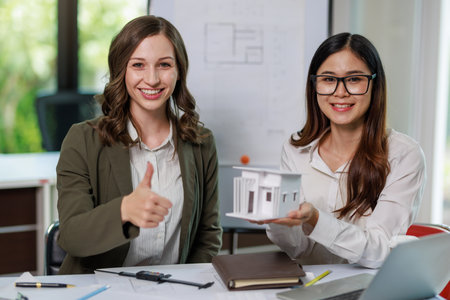 Construction concept of Engineer and Architect working with Construction model and blueprint before buit at site, Engineer and Architect discussing construction plan with computer laptop calculatorの写真素材