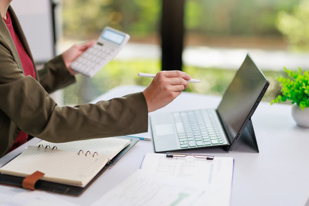 Concept of business office woman working,Closeup businesswoman checking her invesment plan with analyzing document and business investment graph data by using calculator and laptopの写真素材