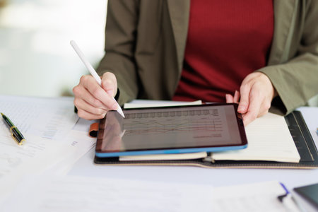 Concept of business office woman working,Closeup businesswoman checking her invesment plan with analyzing document and business investment graph data by using calculator and laptopの写真素材