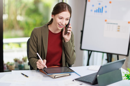 Concept of business office woman working,Businesswoman smile while working about her invesment plan with analyzing document and business investment graph data by using laptop on desk in workstation.の写真素材