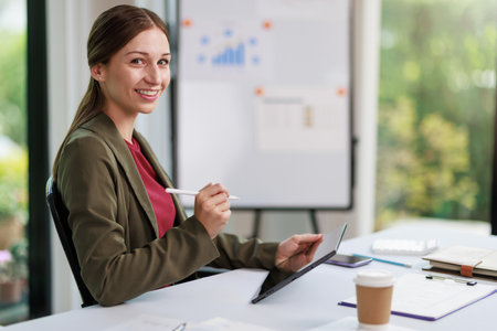 Concept of business office woman working,Businesswoman smile while working about her invesment plan with analyzing document and business investment graph data by using laptop on desk in workstation.の写真素材