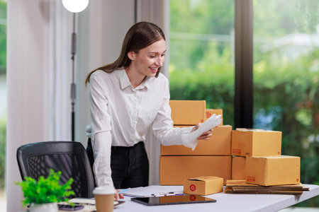 Concept of parcel delivery and selling online,Retailer Using a calculator to calculate sales for the day on an online store for pack into the parcel box and prepare to send the product to the customerの写真素材