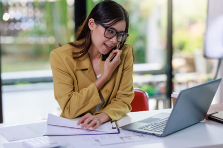 Concept of business office woman working,Businesswoman smile while working about her invesment plan with analyzing document and business investment graph data by using laptop on desk in workstation.の写真素材