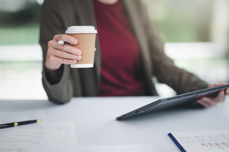 Concept of business office woman working,Businesswoman smile while working about her invesment plan with analyzing document and business investment graph data by using laptop on desk in workstation.の写真素材