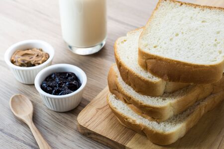 wooden board with Breakfast bread slices with milk on the wooden table. Black currant jam and Peanut butter in the small cup. Selective focus.
の写真素材
