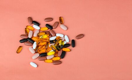 Fishoil capsules and Multivitamin supplements on the pink background with copy space.の写真素材