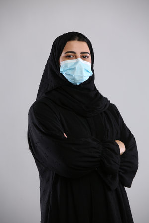 Muslim woman wearing face mask with arms crossed isolated on white background.の写真素材